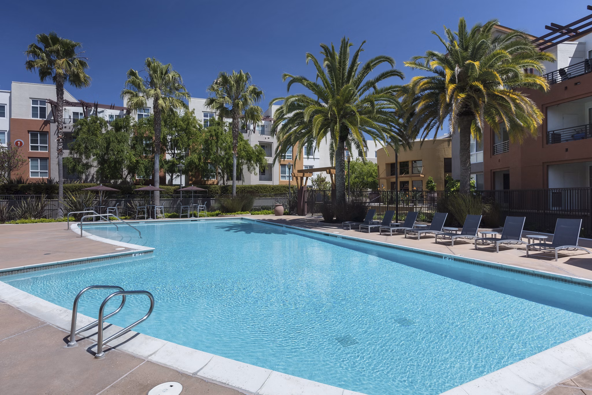 Luxurious outdoor pool at Domicilio Apartments, featuring comfortable loungers and landscaped surroundings for a relaxing experience