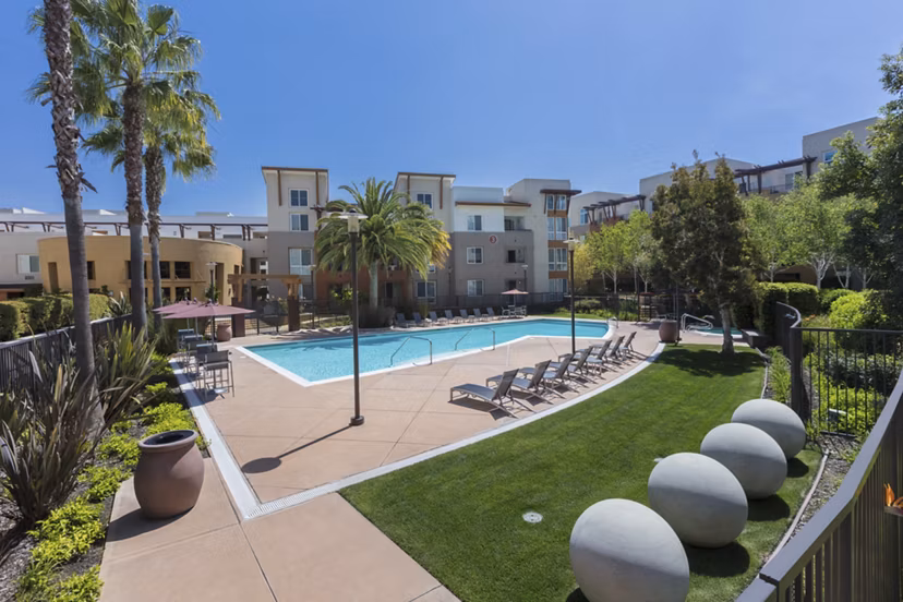 Luxurious pool with lounge chairs at Domicilio Apartments