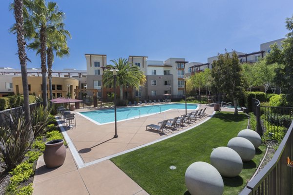 Luxurious pool with lounge chairs at Domicilio Apartments