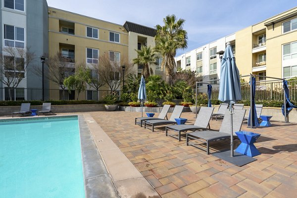 Luxury resort-style pool at Mosaic Apartments with sun loungers and lush landscaping, perfect for relaxation and recreation