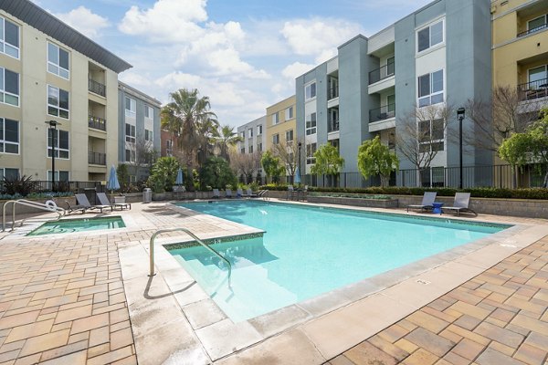 Luxurious pool area at Mosaic Apartments offering a relaxing retreat with stylish loungers and lush landscaping