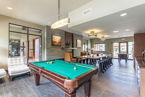 Vibrant games area with pool table and lounge chairs at The Artisan Apartments