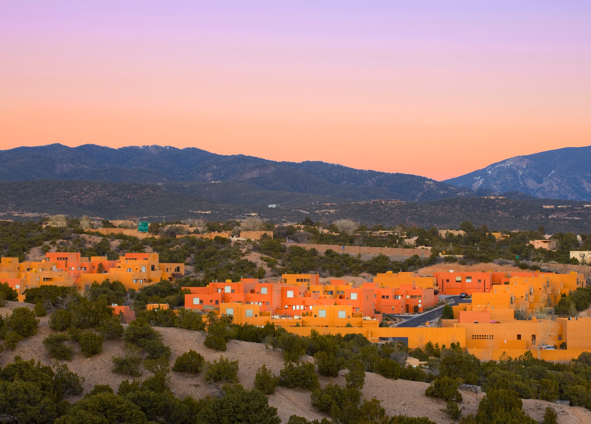 Colorful luxury apartments with trees and mountains in the background during a sunset in a vibrant residential area