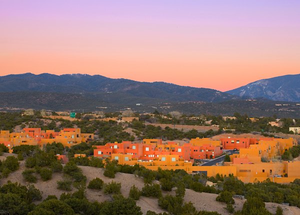 Colorful luxury apartments with trees and mountains in the background during a sunset in a vibrant residential area