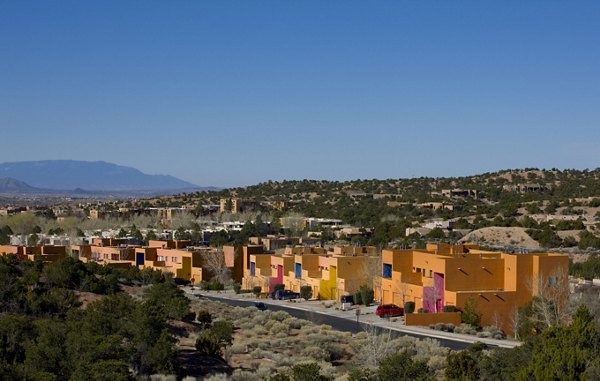 Colorful luxury apartments amidst desert landscape with lush vegetation and hills in the background