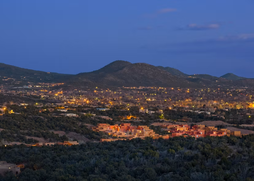 Twilight landscape view of a city skyline with hills in the background near luxury apartments