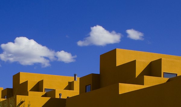 Modern luxury apartments with geometric design and bright yellow facade under a blue sky