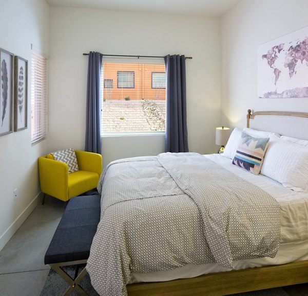 Cozy bedroom featuring a comfortable bed and vibrant yellow chair with wall art and curtains