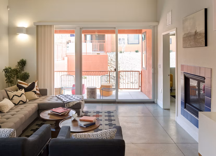 Modern living room with sectional sofa and fireplace, featuring large sliding doors to outdoor space in luxury apartment