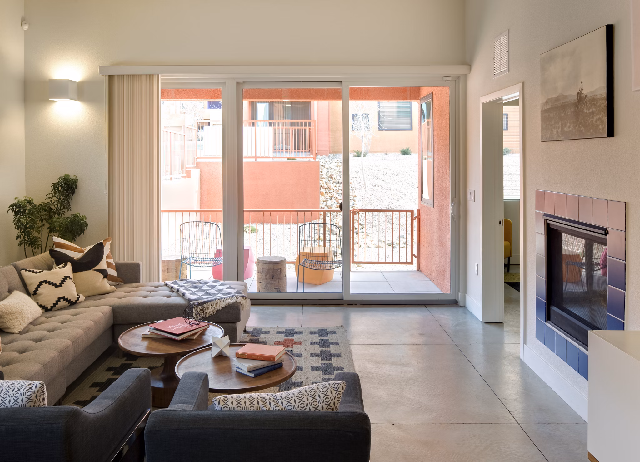 Modern living room with sectional sofa and fireplace, featuring large sliding doors to outdoor space in luxury apartment