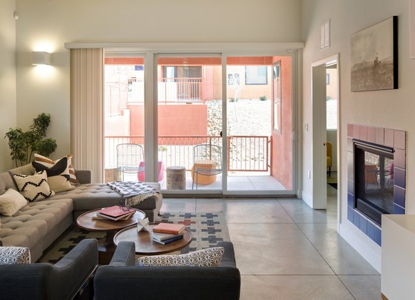 Modern living room with sectional sofa and fireplace, featuring large sliding doors to outdoor space in luxury apartment
