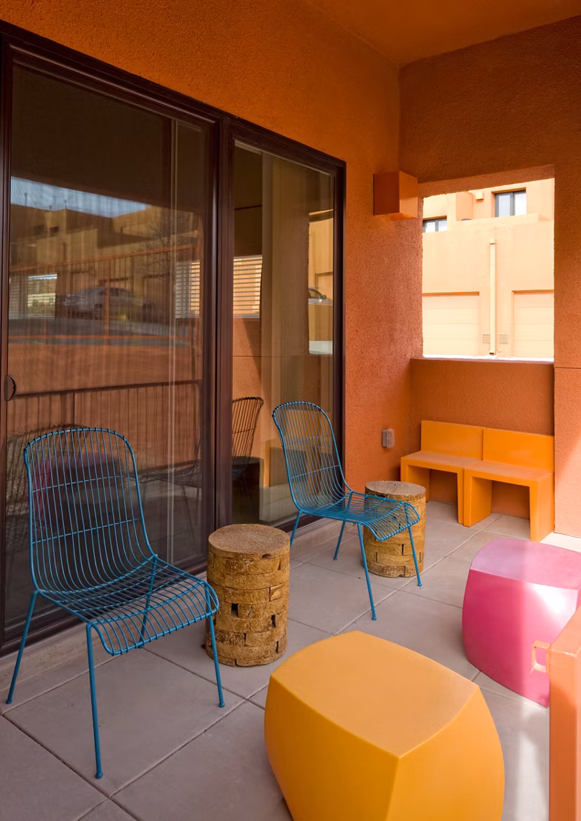 Patio seating area with wire chairs, round tables, and colorful geometric stools at luxury apartments