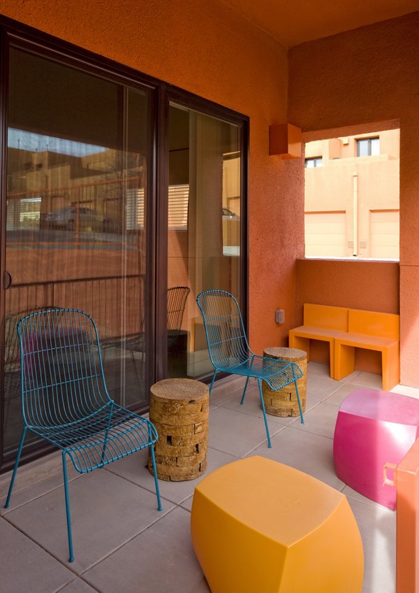 Patio seating area with wire chairs, round tables, and colorful geometric stools at luxury apartments