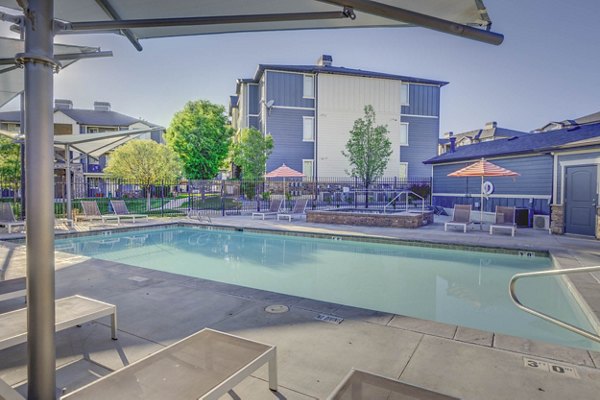 Outdoor pool with lounge chairs at Villas on Main Apartments featuring serene water views for relaxation and enjoyment