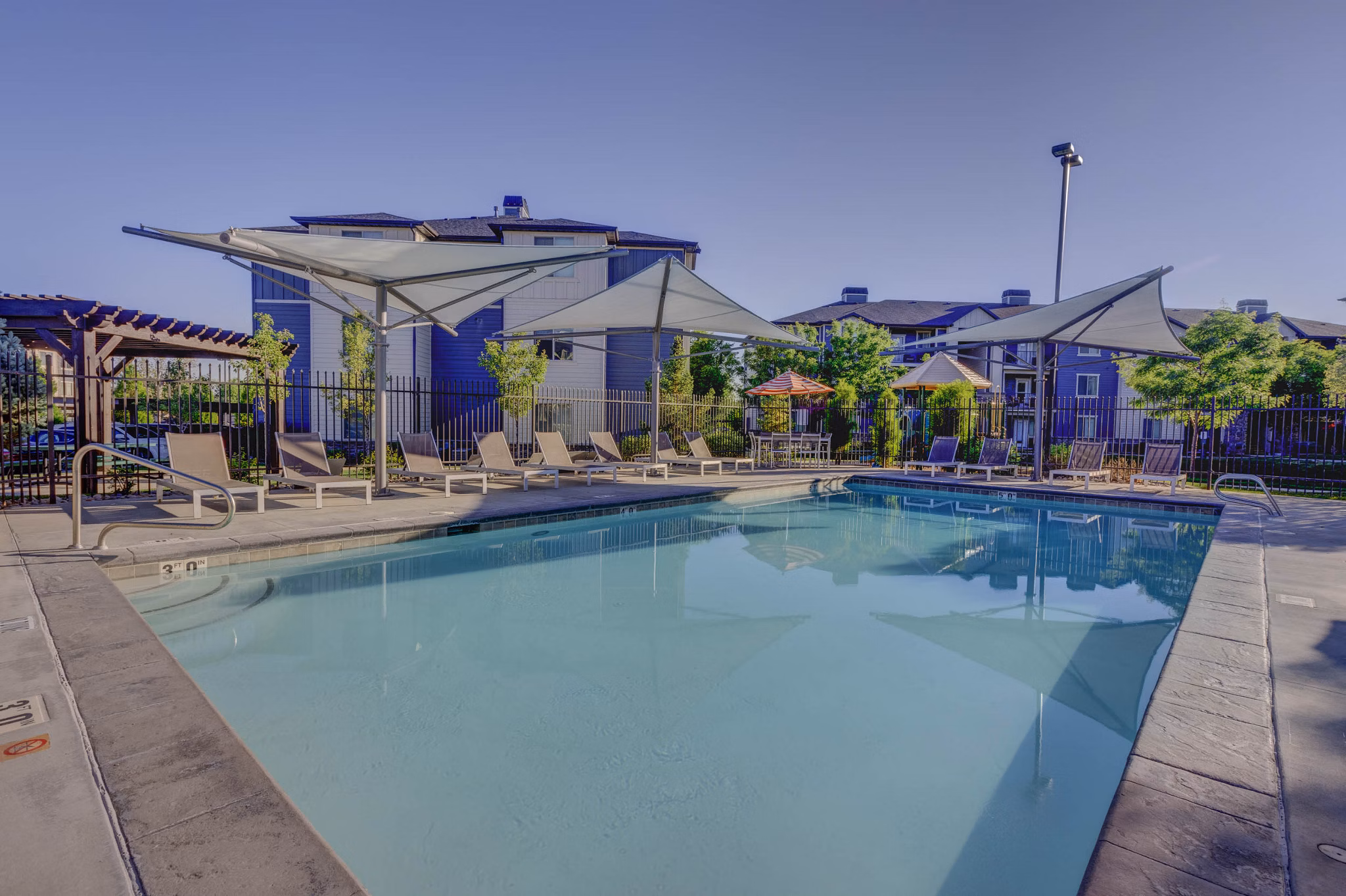 Resort-style swimming pool with lounge chairs at Villas on Main Apartments