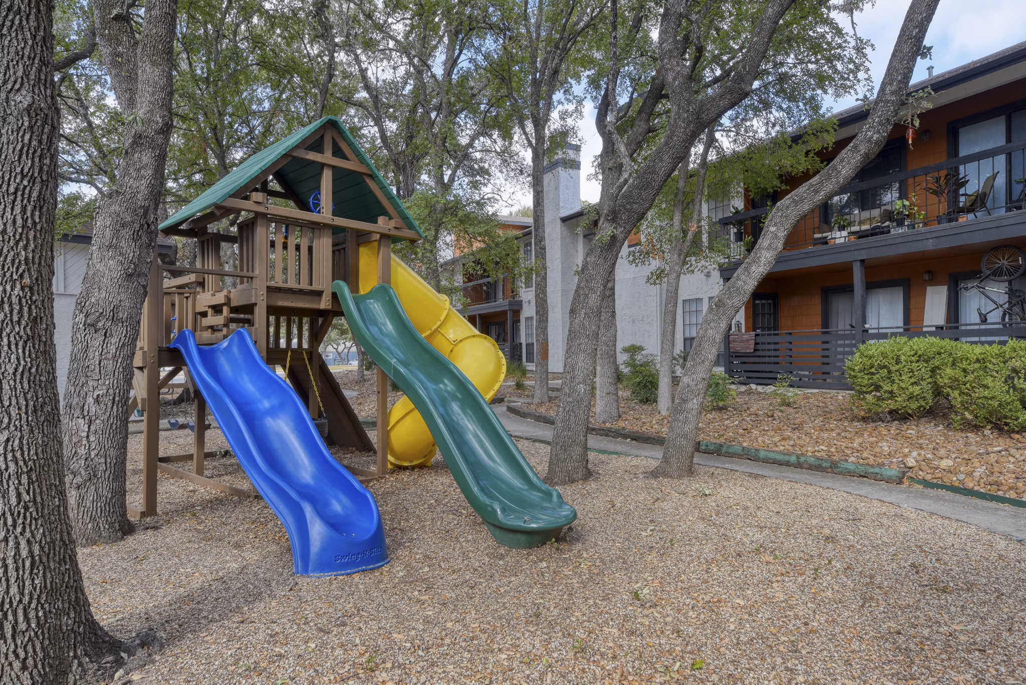 Colorful playground for children at Landera Apartments, featuring slides and swings, perfect for family fun and outdoor play