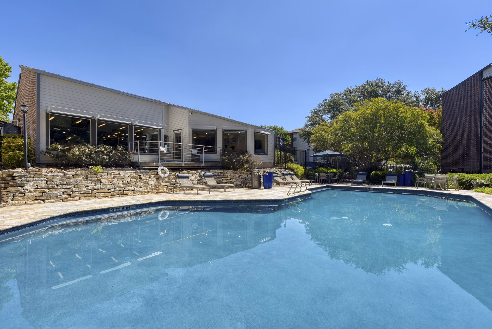 Relaxing poolside area at Broadstone Medical Apartments with lounge chairs and lush landscaping