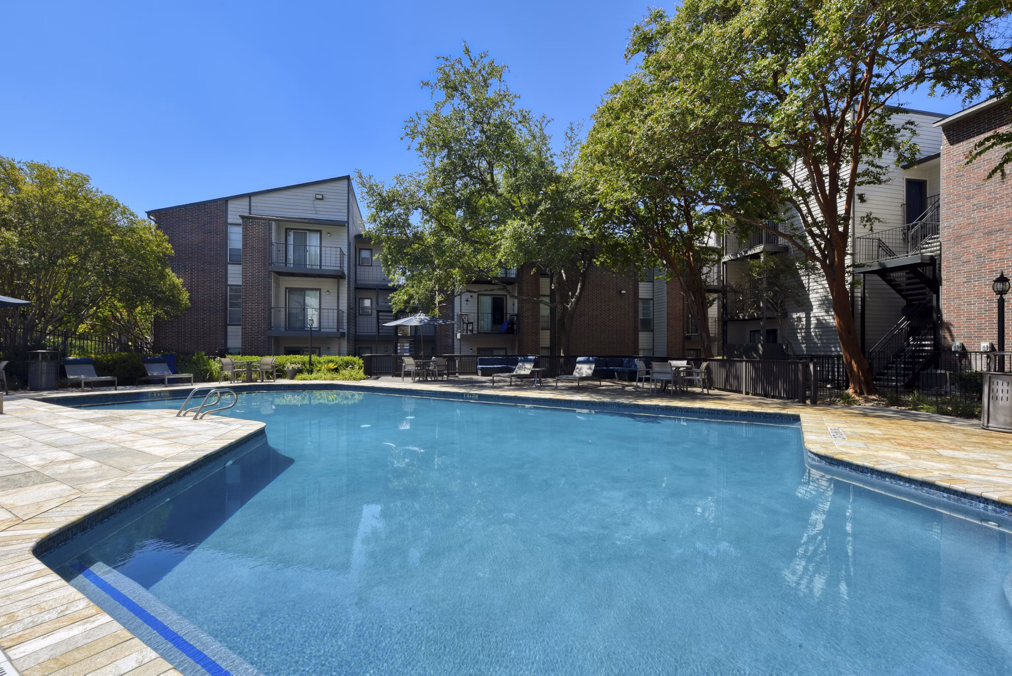 Serene pool area at Broadstone Medical Apartments with sun loungers and lush greenery, offering relaxation and leisure