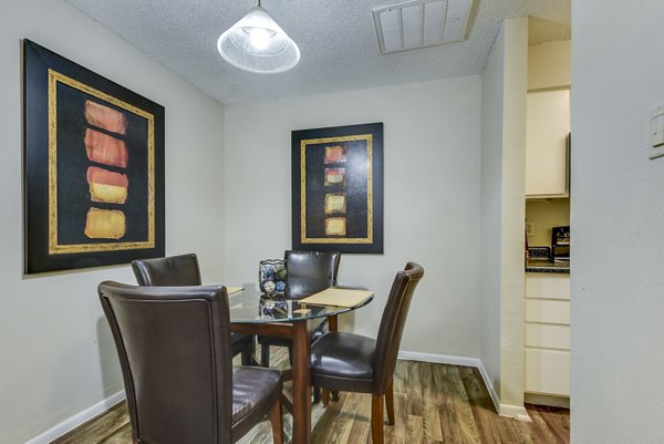 Dining area with modern furnishings and large windows at Woods of Elm Creek Apartments