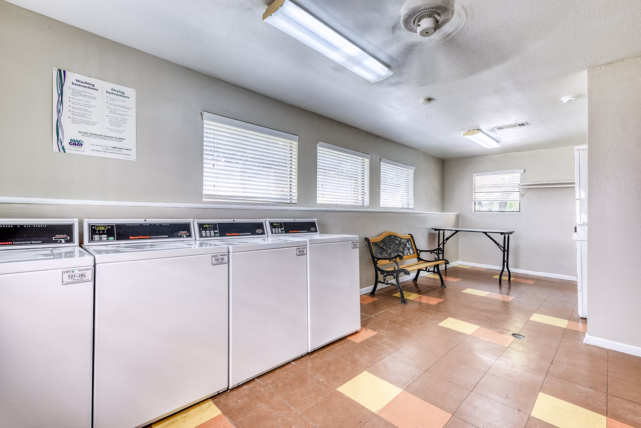 Modern laundry facility at Woods of Elm Creek Apartments with energy-efficient machines and ample folding space