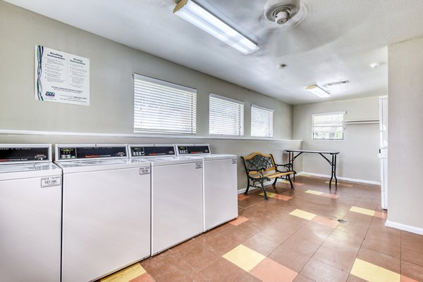 Modern laundry facility at Woods of Elm Creek Apartments with energy-efficient machines and ample folding space