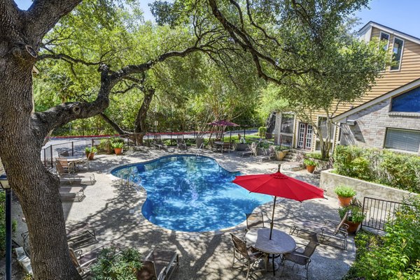 Luxury pool surrounded by lush greenery at Woods of Elm Creek Apartments