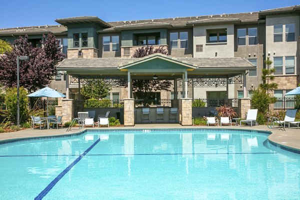 Resort-style pool at Fiori Estates Apartments with lounge chairs and palm trees, offering a luxury retreat for residents
