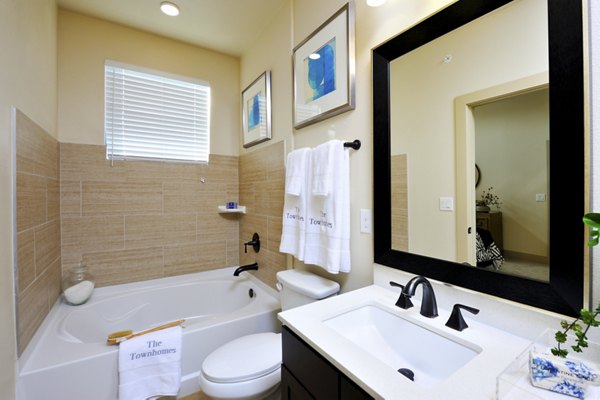 Modern bathroom featuring sleek fixtures and granite countertops in The Townhomes at Woodmill Creek