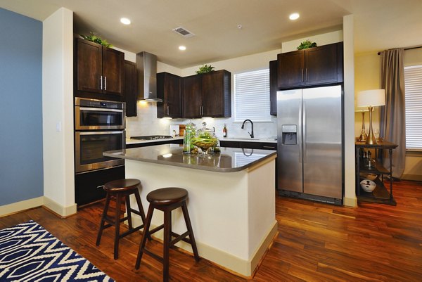 Modern kitchen with granite countertops and stainless steel appliances in The Townhomes at Woodmill Creek