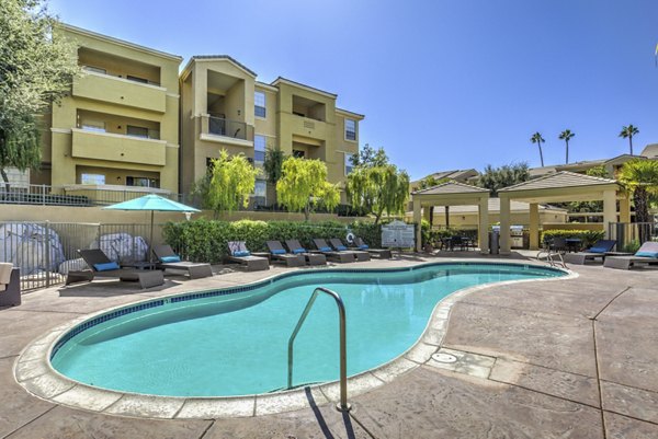Luxury pool area at Stone Canyon Apartments with lounge seating and palm trees, offering a relaxing ambiance for residents