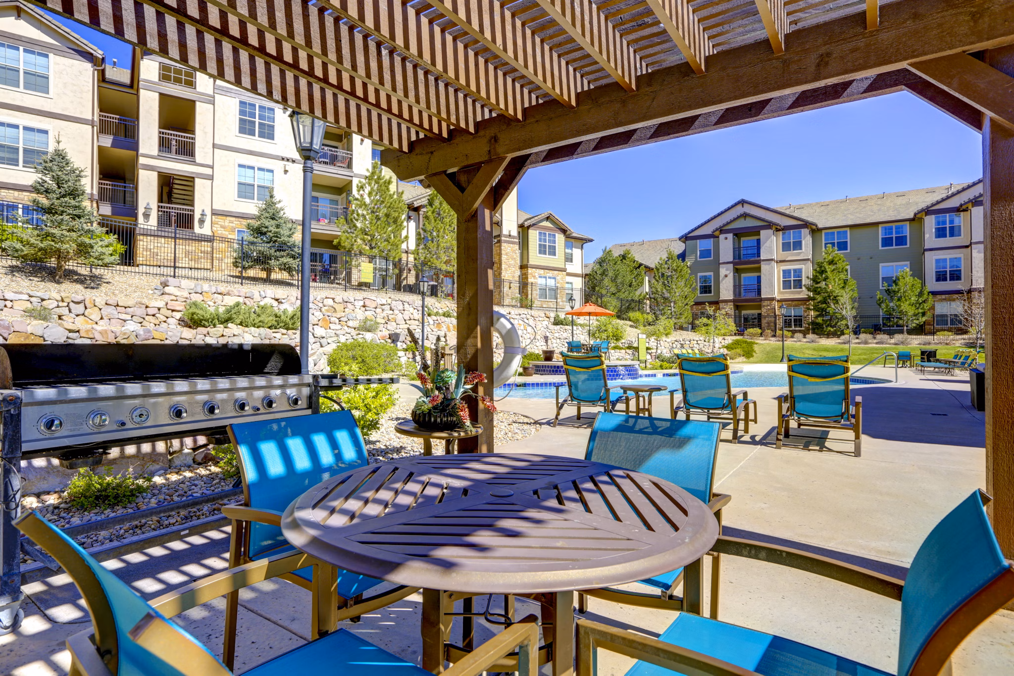 Outdoor grill area and patio with seating at Canyons at Saddle Rock Apartments, ideal for social gatherings and barbecues