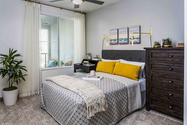 Bright bedroom with modern furnishings at Jefferson Platinum Triangle Apartments, reflecting luxury living in a Greystar community