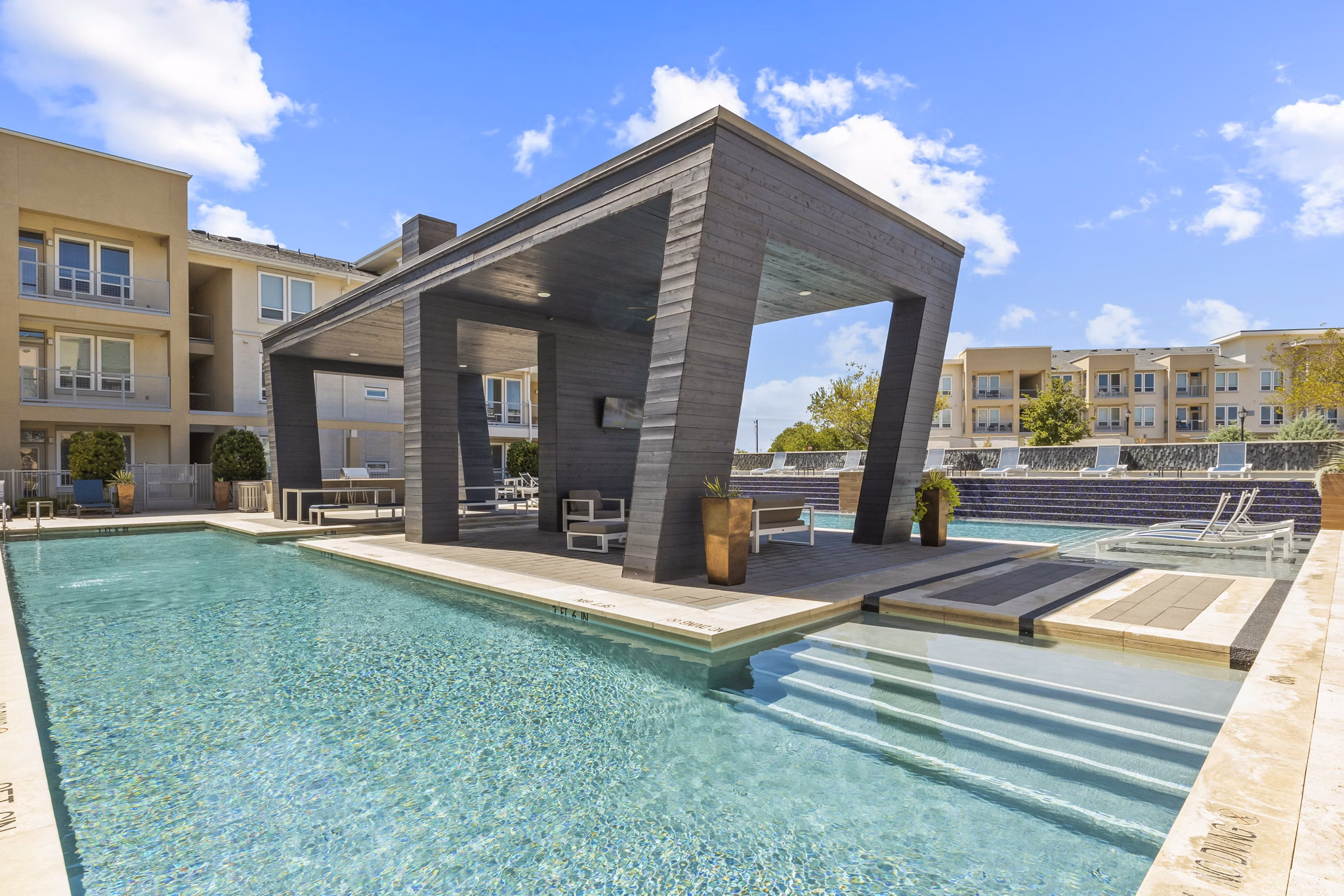 Pool with lounge chairs at Avenue 900 Apartments, offering luxury amenities in a serene setting
