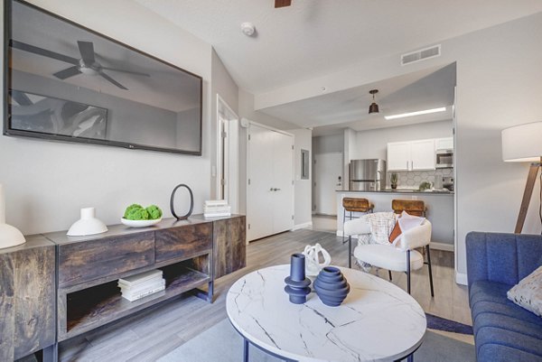 Living room featuring modern furniture and natural light at The Essex Apartments