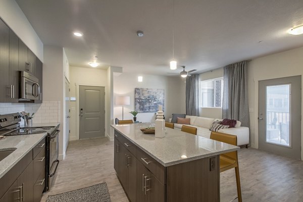 Modern kitchen featuring stainless steel appliances and large island at One West Apartments