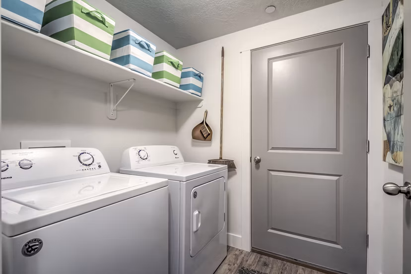 Laundry room with modern washers and dryers at One West Apartments in luxury Greystar community