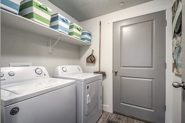 Laundry room with modern washers and dryers at One West Apartments in luxury Greystar community