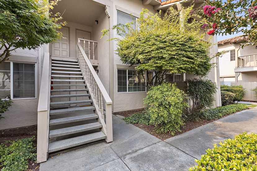 Exterior view of luxury apartments with a staircase and landscaping in a serene setting