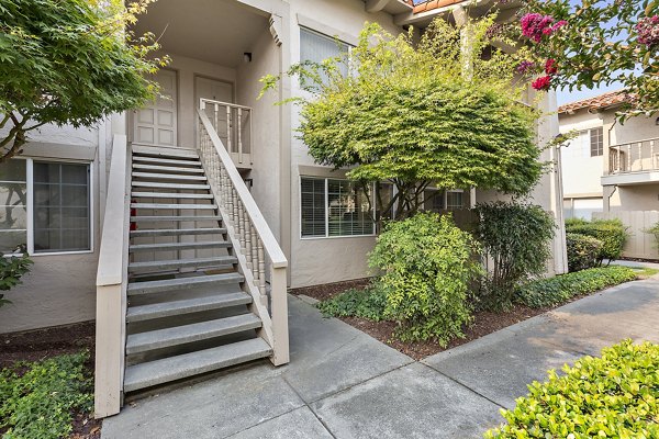 Exterior view of luxury apartments with a staircase and landscaping in a serene setting
