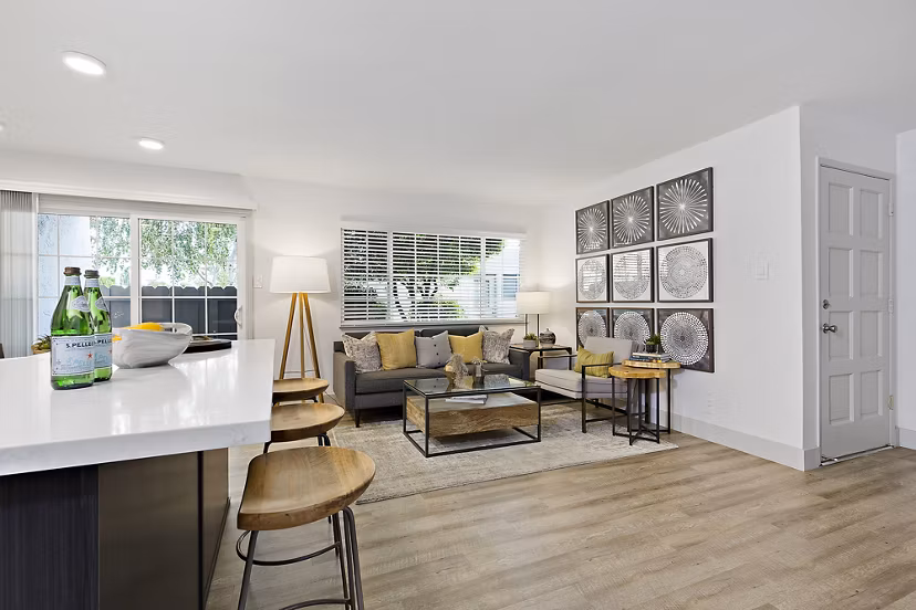 Modern living room and kitchen with sofa, bar stools, and wall art in luxury apartments
