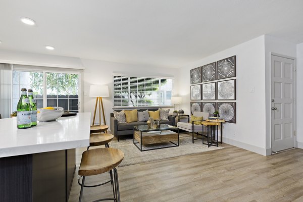 Modern living room and kitchen with sofa, bar stools, and wall art in luxury apartments
