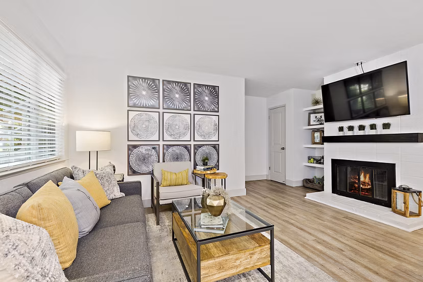 Modern living room with stylish sofa, armchair, fireplace, and wall art in luxury apartments