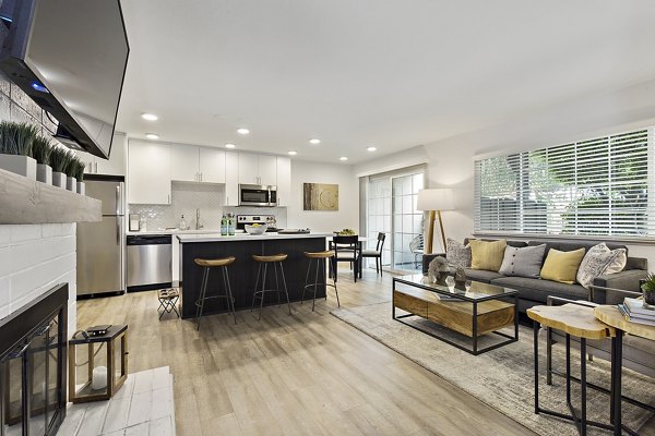 Spacious modern living room and kitchen featuring a fireplace and stainless steel appliances in luxury apartment