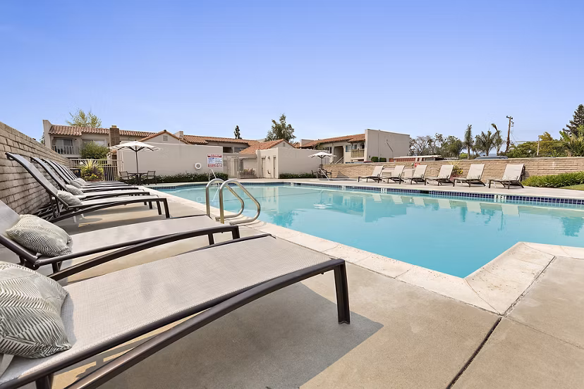 Outdoor swimming pool with lounge chairs and modern apartment building in the background