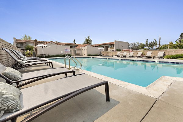 Outdoor swimming pool with lounge chairs and modern apartment building in the background