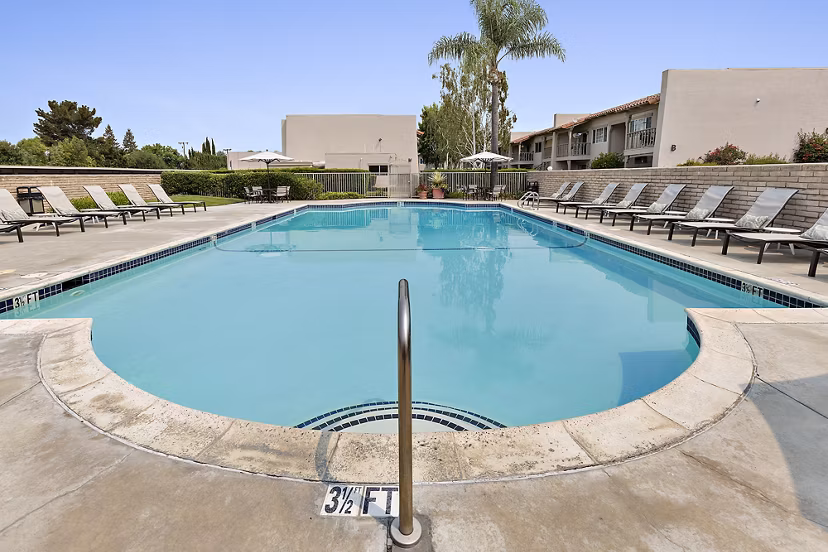 Relaxing swimming pool surrounded by red Adirondack chairs at luxury apartments