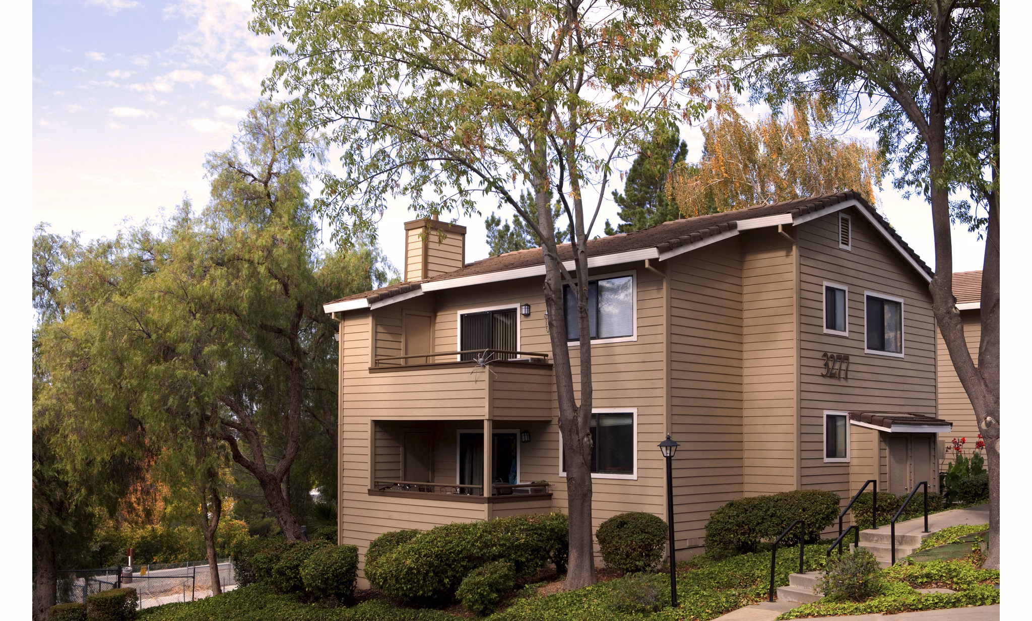 Lime Ridge Apartments: Two-story beige luxury apartments surrounded by lush greenery