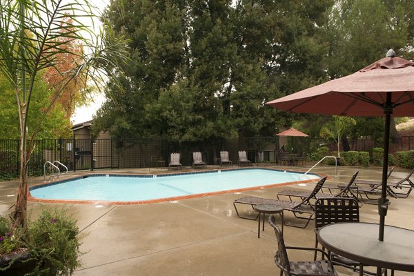 Lime Ridge Apartments: Outdoor pool area with lounge chairs and umbrellas, ideal for luxury living