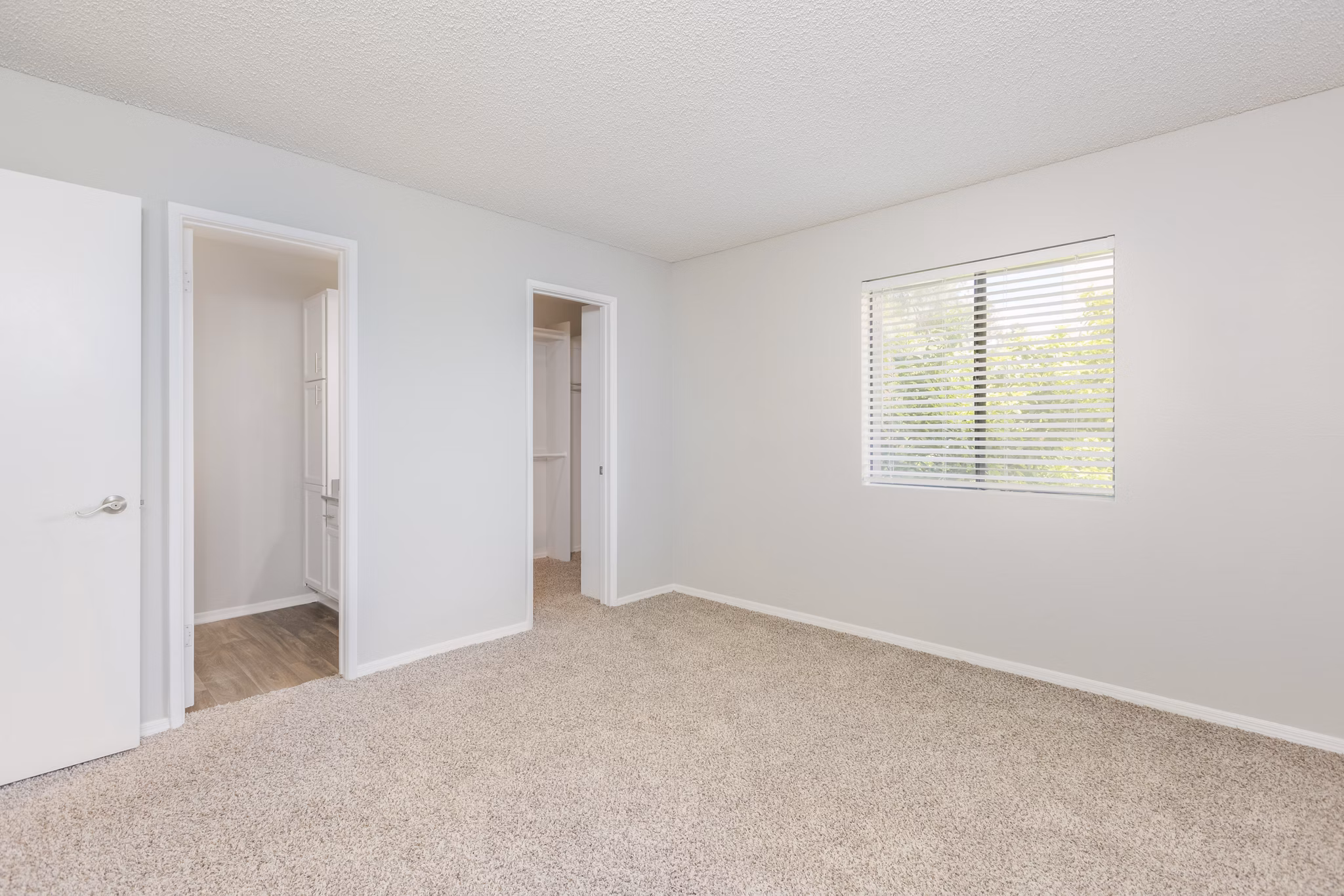 Cozy bedroom featuring sleek furnishings and large windows at The Bella Apartments