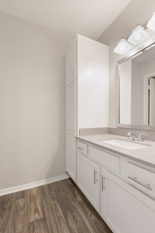 Modern bathroom with marble countertops and glass shower in The Bella Apartments
